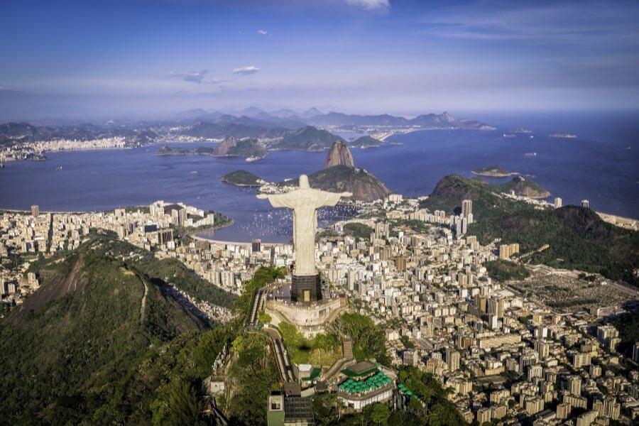 Aerial view of Rio de Janeiro with the famous Christ the Redeemer statue in the foreground, overlooking the sprawling city and the Botafogo Bay, a popular destination on cruise routes in South America.