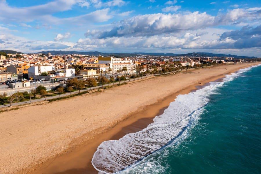 The golden sandy beach of Malgrat de Mar in Catalonia, on the Costa Barcelona. In the background, the city begins, separated by a promenade.