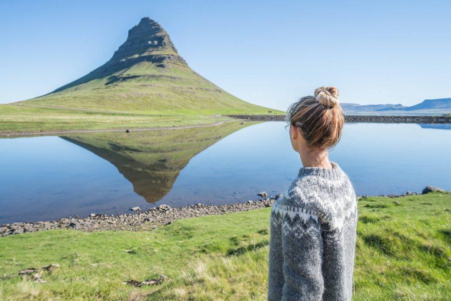 A woman stands before the Kirkjufell mountain in Iceland