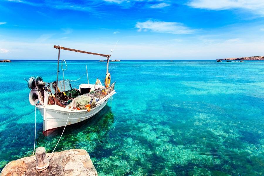 Els Pujols beach in Formentera with traditional fishing boat on a summer day.