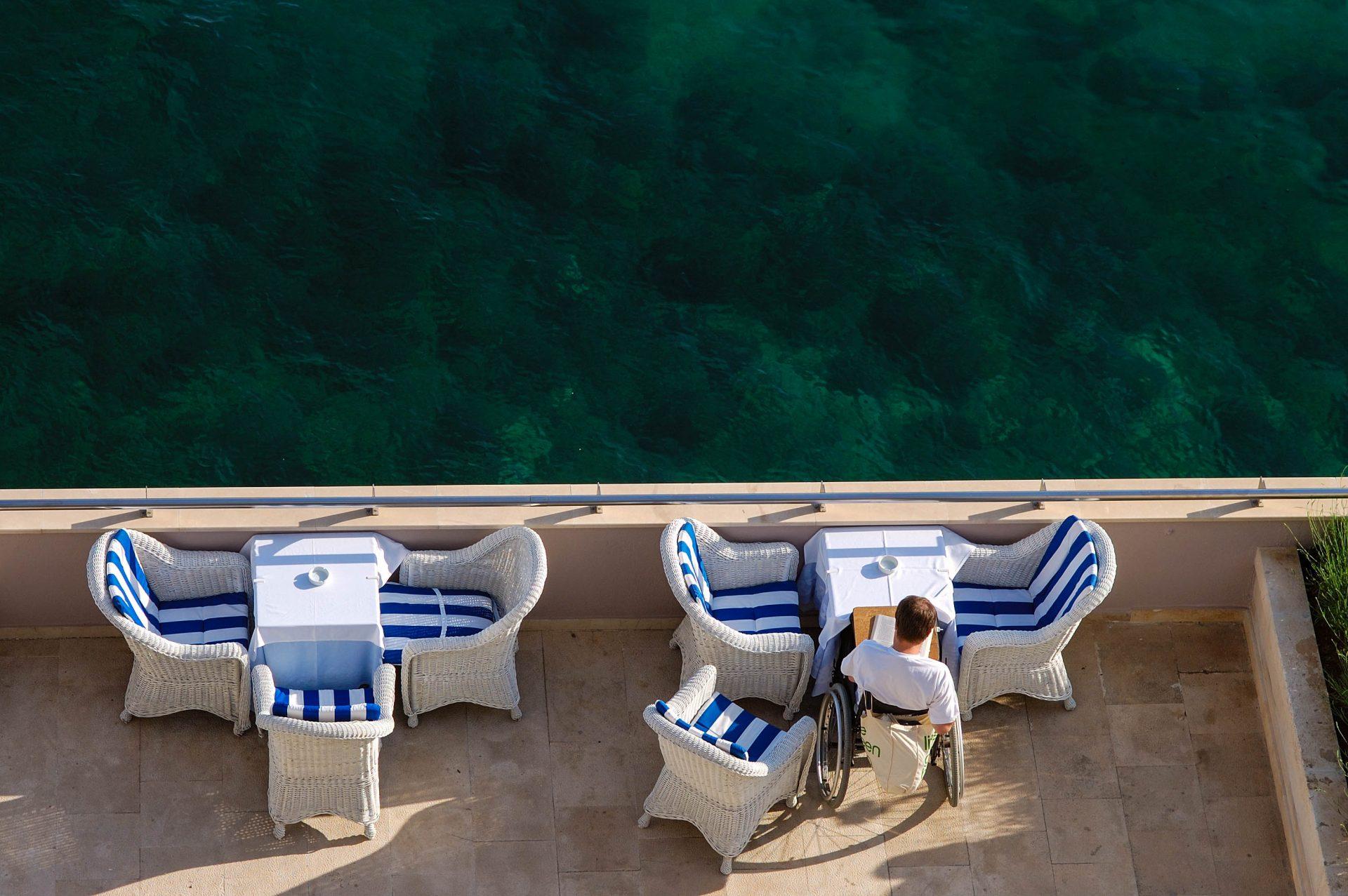 A man sits with a wheelchair on the hotel terrace