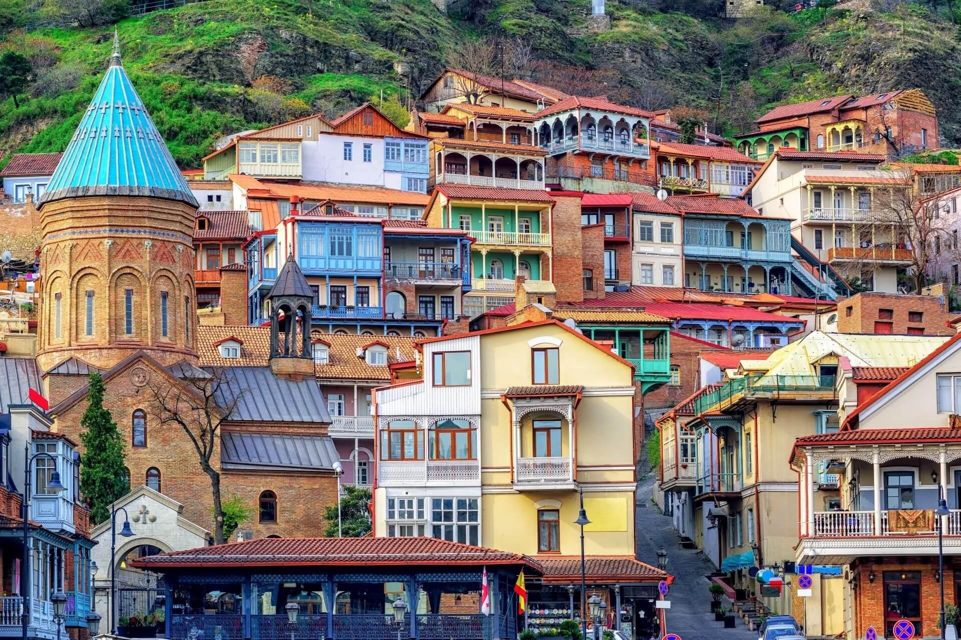 In Georgia, colorful house facades are lined up closely together. Most are equipped with elaborately decorated balconies and are built up the hill.