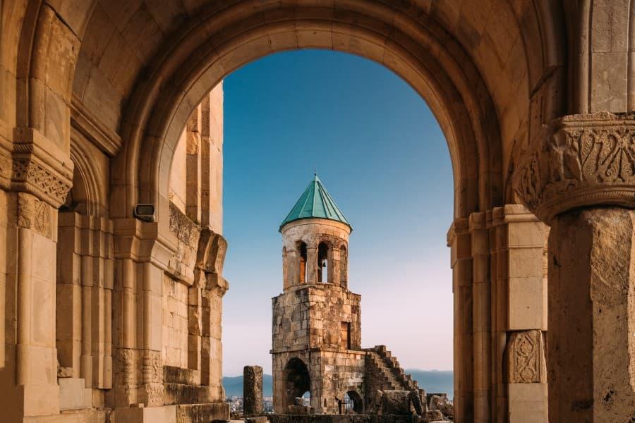 In the foreground, you see an arch of the Bagrati Cathedral in Kutaisi. Through this arch, one of the towers with a blue slate roof is photographed.