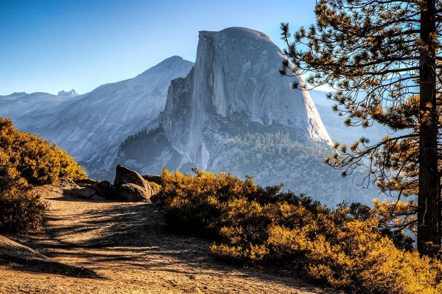 The trail to Half Dome in Yosemite National Park in the USA is one of the most challenging in the country. The picture shows the massive half-round rock formation named Half Dome. In the foreground, the trail runs