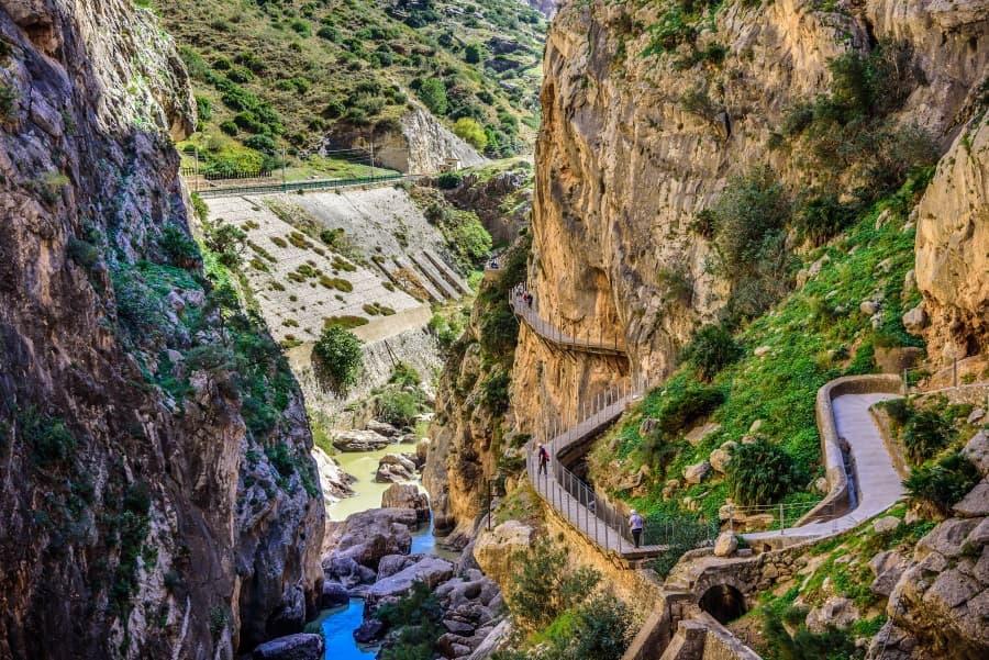 The path of Caminito del Rey leads you on wooden pathways through a canyon, with a river flowing below. The sheer walls rise beside you.