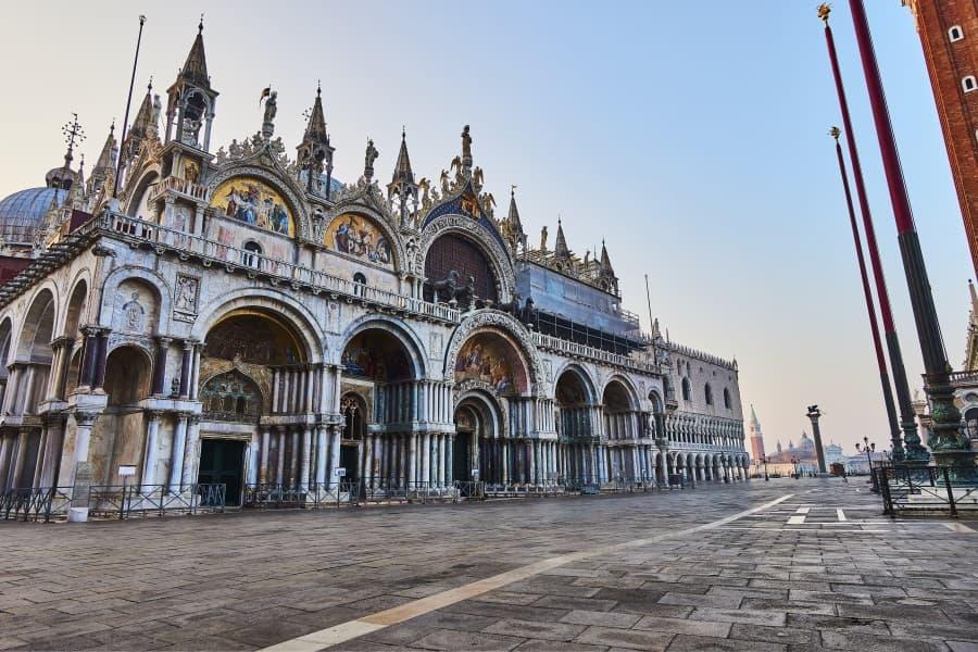 View of the magnificent Basilica di San Marco in Venice with its Byzantine domes and mosaics. In the foreground, an empty, wide square, left the imposing façade of the basilica.