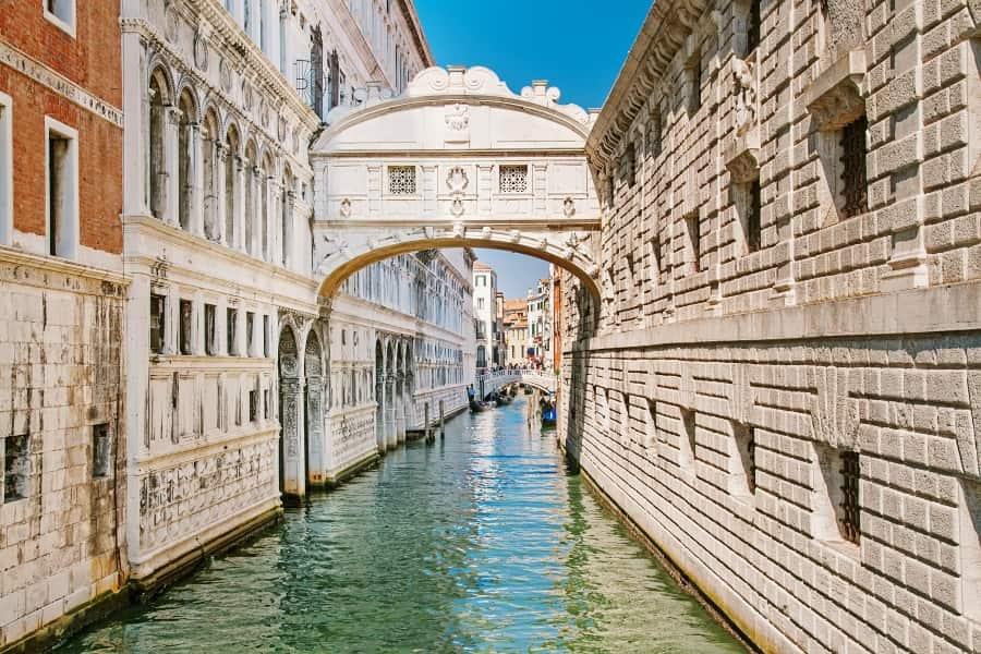 View from the canal of the Bridge of Sighs in Venice, which is embedded between two buildings and thus hangs a few meters higher than the other bridges. The Bridge of Sighs is a closed or covered bridge made of light stone and elegantly decorated.