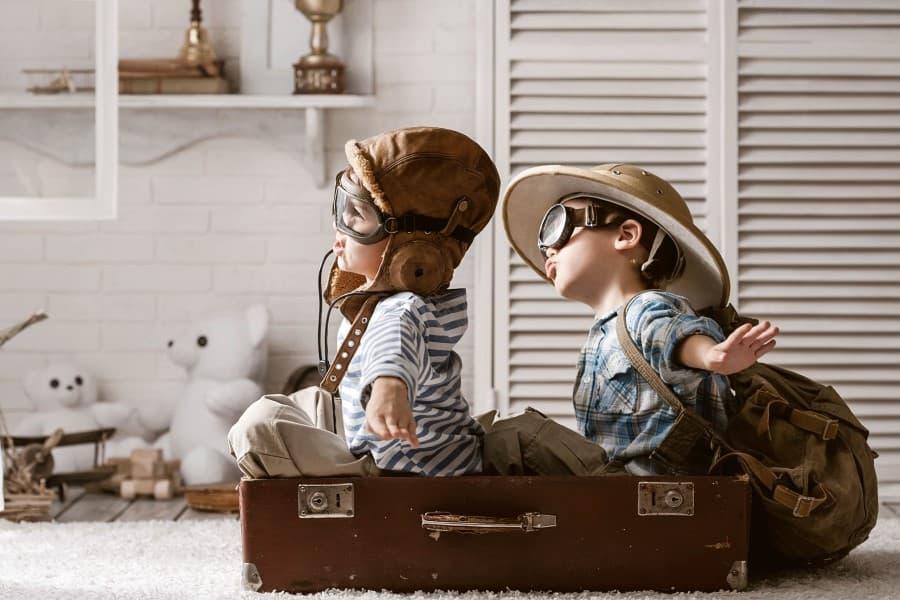 Two boys dressed as an aircraft pilot and traveler playing in their room