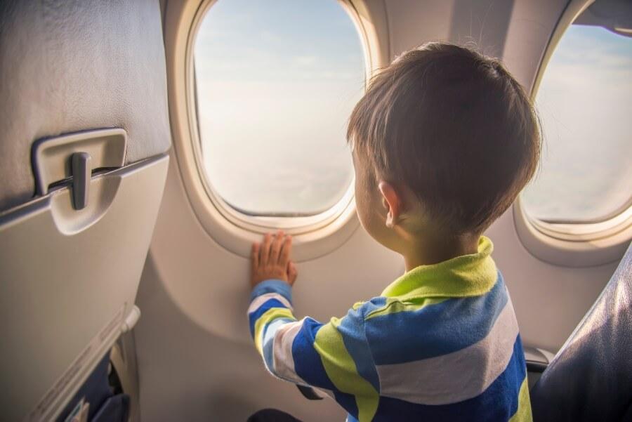 Boy sitting on the airplane and looking out the window