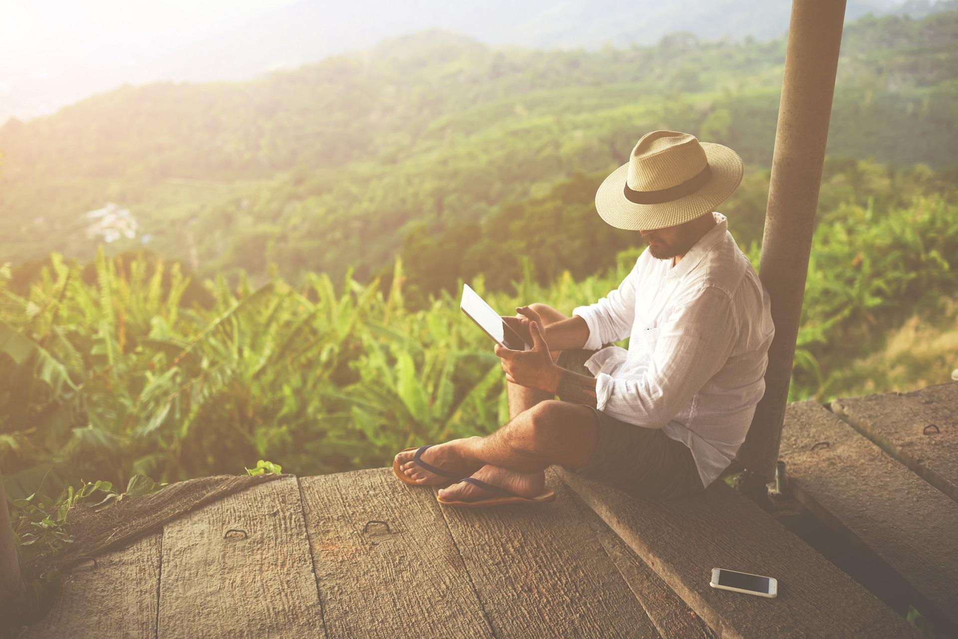 A young man sitting with his tablet in the jungle