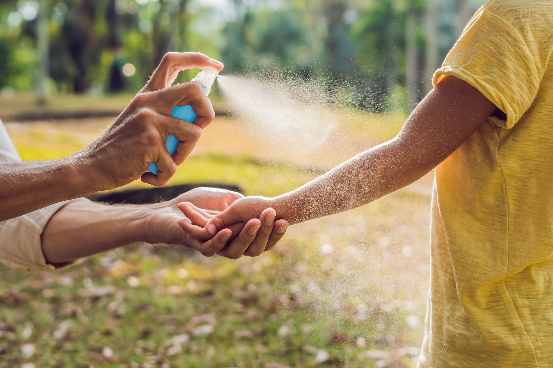 A mother spraying her child with mosquito repellent