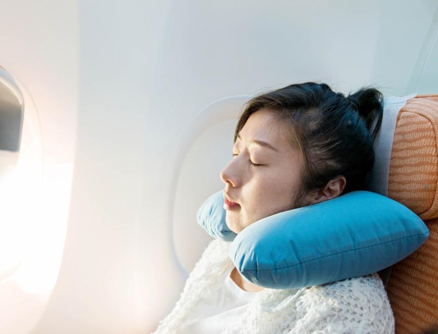 Young asian woman sleeping on an airplane next by the window.