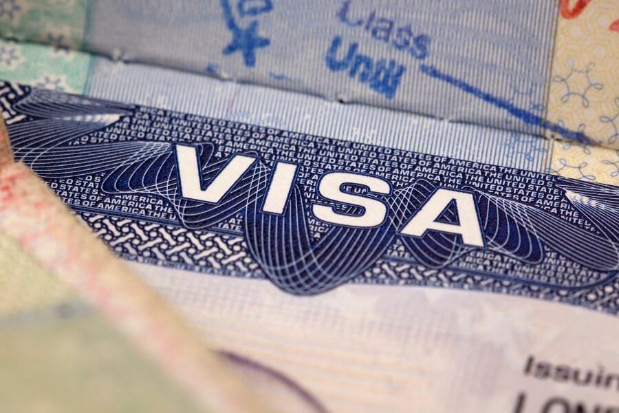 Large blue lettering 'Visa' in the center of a passport. Surrounded by fine, swirling line patterns and lines of text that typically represent visa details.