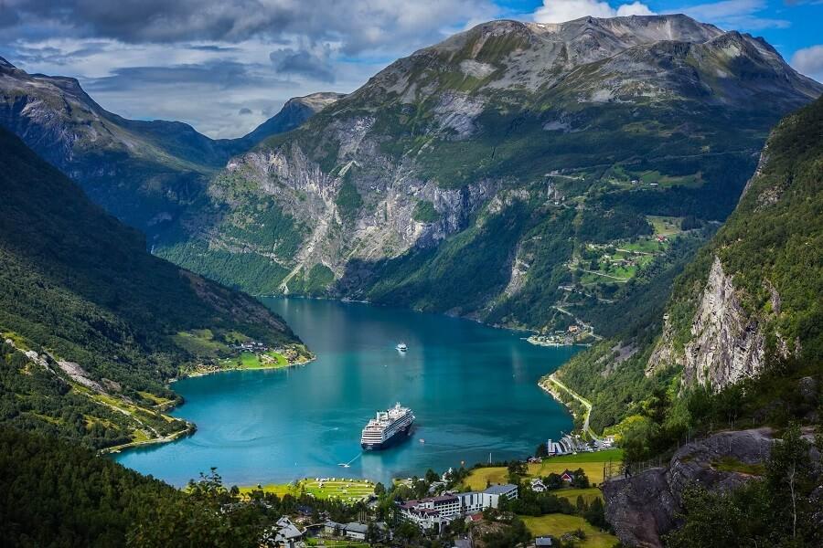 View of Geirangerfjord with a cruise ship. The picture is framed by green nature and mountains.