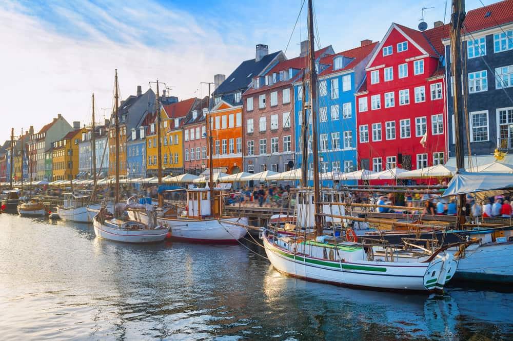 Copenhagen: Colorful houses photographed from the water. In the foreground are small sailboats.