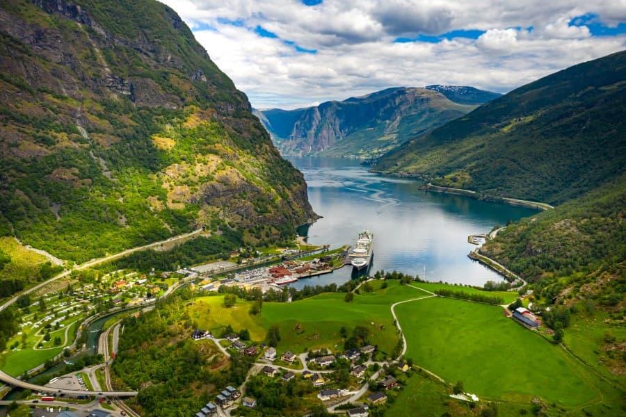 Cruise ships in the fjord, surrounded by green mountains and a small village in Norway.