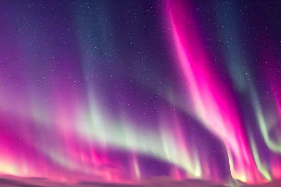 Pink Northern Lights dancing in the night sky, interspersed with green and purple tones. Stars twinkle in the background. The Northern Lights extend vertically across the entire image.