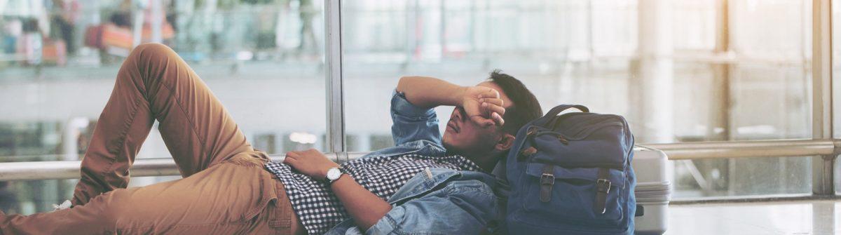 Asian young man waiting at the airport terminal for his delayed flight