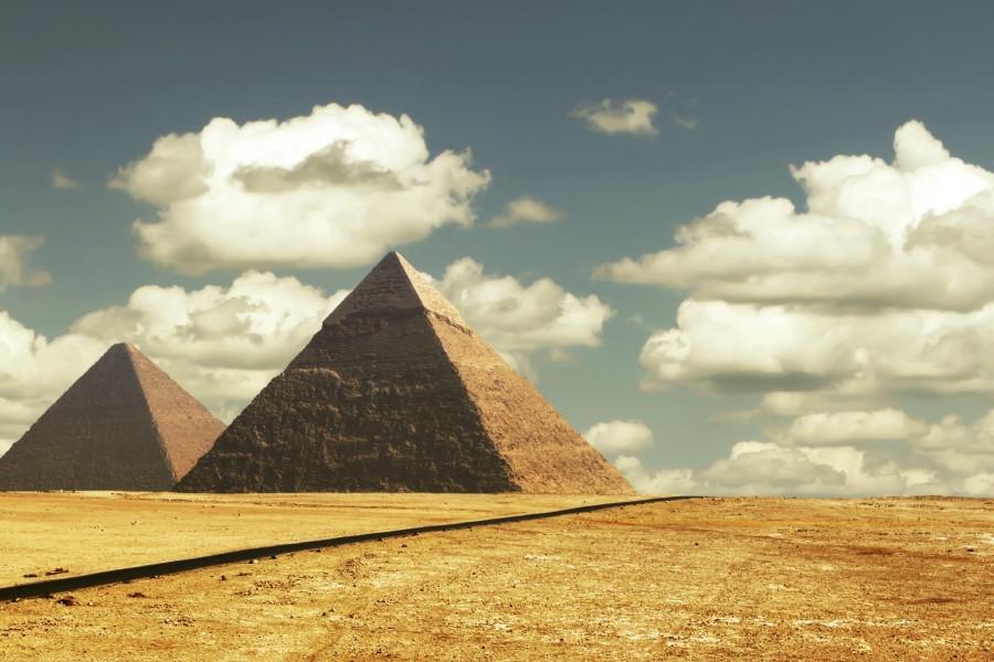 Two of the Pyramids of Giza in the desert. White clouds in the blue sky.