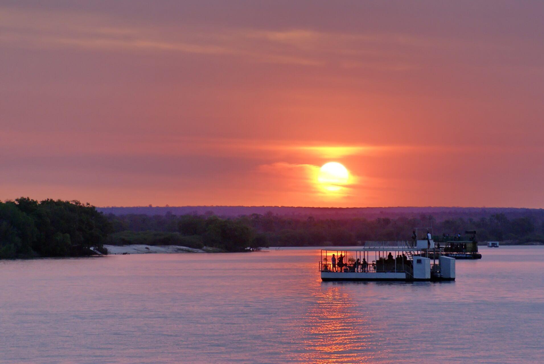 Boats with tourists sailing at sunset over the Zambezi River in Zimbabwe.