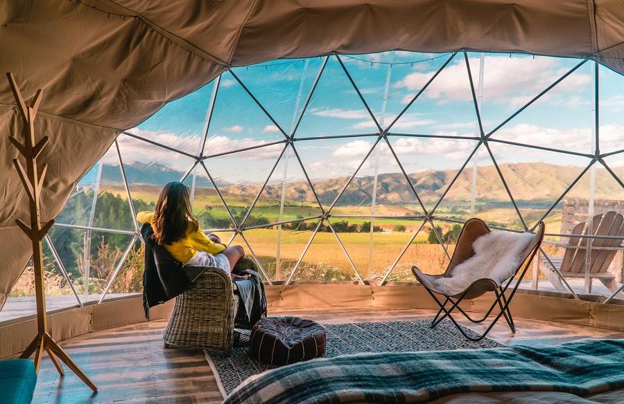 Woman looking out at nature from Geo Dome tents. Green
