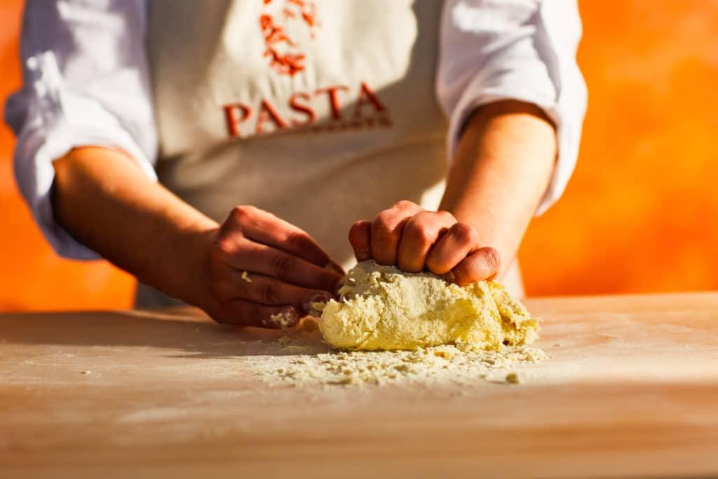 a pasta maker in the process of kneading pasta dough