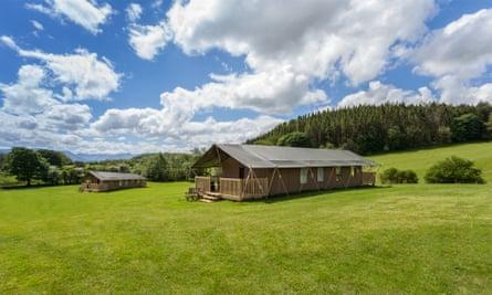 Canvas lodges at Wonderfully Wild, Beaumaris, Anglesey, Wales. Fluffy white clouds are dotted across a blue sky above them.